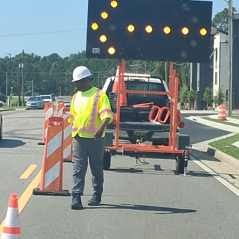 man next to cones and detour sign