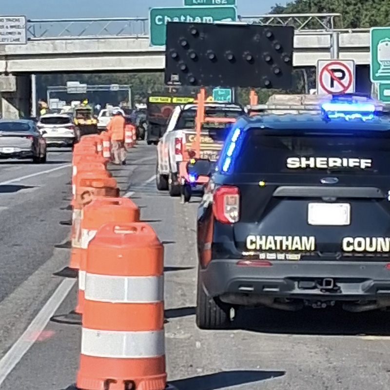 police car behind traffic barrels on a road